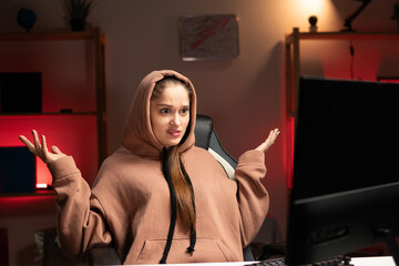 Young beautiful woman programmer in hoodie working overtime at night using pc at home, with...