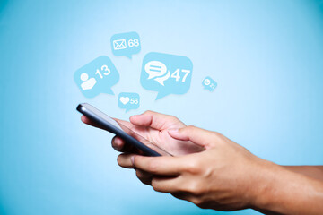 Close-up of man's hand using smartphone to play social media with emoticons or notifications popup.