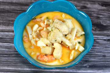 assorted seafood creamy soup of shrimps, squid, crabs, fish fillet, herbs, dill, garlic and onion, seafood mixture hot soup, healthy food concept of pieces of various sea food, selective focus
