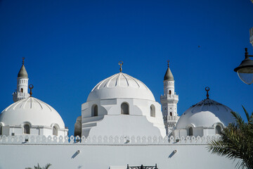 Magnificent Domes and Minarets of the Quba Mosque with white domes and minarets against a vibrant...