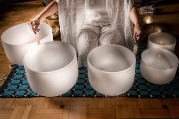 Woman in Sound healing therapy with crystal bowls and Yoga meditation uses aspects of music to...