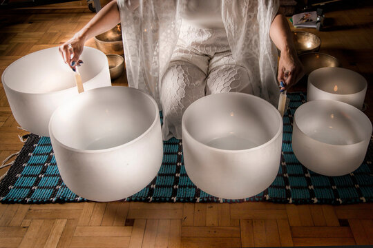 Woman in Sound healing therapy with crystal bowls and Yoga meditation uses aspects of music to improve health and wellbeing. sound therapy instruments can help your meditation and relaxation.     
