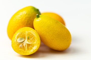 Ripe Chinese mandarins, or Kingen, on white wooden surface.