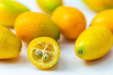 Ripe Chinese mandarins, or Kingen, on white wooden surface.