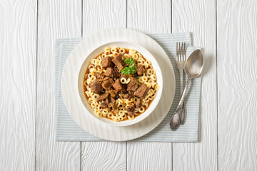 pasta rings topped with braised meat in bowl