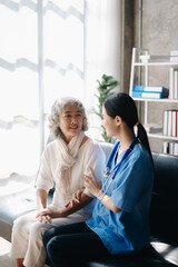 Asian caregiver doctor examine older patient woman therapist nurse at nursing home taking care of senior elderly woman sit on sofa