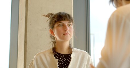A young woman displays a surprised expression, characterized by wide eyes. Her face captures a...
