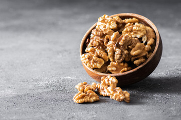Ripe and fresh walnut kernels in bowl or burlap sack without shell on rustic table, healthy nut food for brain