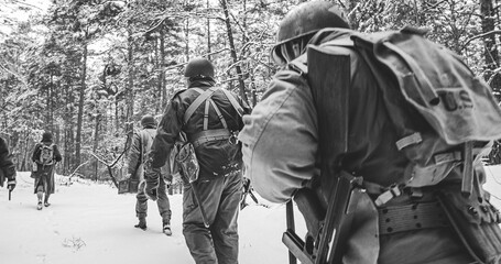 Heroes Of War. Re-enactors Dressed As American Infantry Soldier Marching Through Forest Road In Cold Winter Day. Group Of Usa Soldiers Marching Country Road. Usa Army Soldiers Of World War Ii