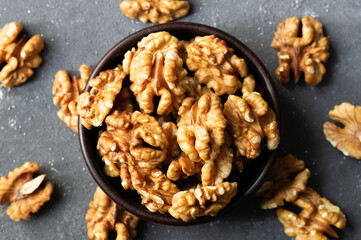 Ripe and fresh walnut kernels in bowl or burlap sack without shell on rustic table, healthy nut food for brain
