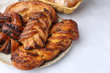 Different sweet pastries on white tiled table, closeup