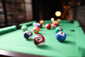 Many colorful billiard balls on green table indoors, closeup