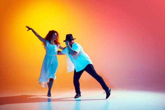Practicing salsa with vigor, dance pair perfects steps, demonstrating their commitment to excellence in Latin dance in neon light. Concept of dance, performance, art, entertainment.