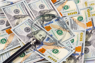 Close up of dollar banknotes and magnifying glass on chart background