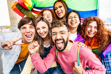 Diverse group of cheerful young people celebrating gay pride day - Lgbt community concept with guys and girls hugging together outdoors