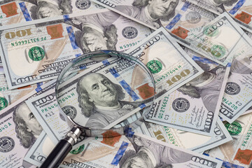 Close up of dollar banknotes and magnifying glass on chart background