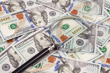 Close up of dollar banknotes and magnifying glass on chart background
