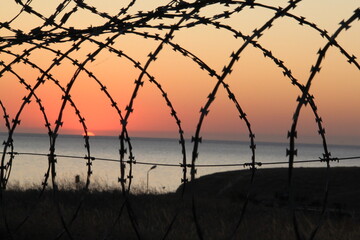 A Beautiful View of Barbed Wire at Sunset Over Calm Water During a Peaceful Evening