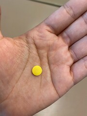 One human hand holds a pill to be taken. person holding a pill. 