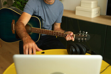 A man sitting in front of the computer practicing online music lessons