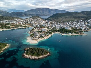 Naklejka premium Aerial view of Ksamil resort village surrounded by blue waters and majestic mountains. Albania