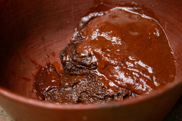 Woman from an indigenous community in Oaxaca preparing traditional Mole Rojo with a metate, a tool for grinding ingredients in Mexico.