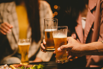 A cheerful group of young adults enjoys a lively night out, raising glasses in a celebratory toast. Laughter and smiles fill the air as friends bond over drinks in a vibrant social gathering.