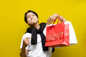 Happy Surprised Young Asian Man Holding Shopping Bags in Excitement