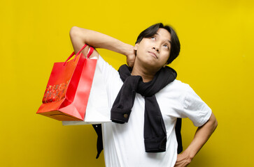Thoughtful Young Asian Man Holding Shopping Bags After Shopping