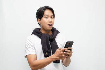 Excited Young Asian Man in Casual Outfit Holding Smartphone with a Joyful Surprise Expression