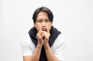 Young Asian man covering his nose and mouth with a disgusted expression