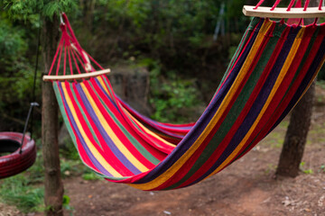A colorful cloth hammock tied to a tree trunk