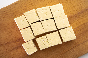 Pieces of raw tofu on a wooden board with soy beans.Vegan food ingredient in Asian cuisine, Plant...
