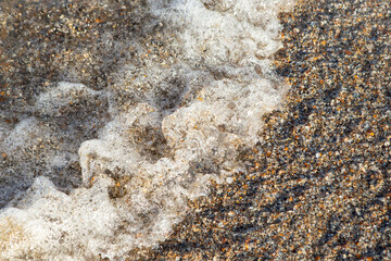Sea water foam on crushed sea shells ans sand, soft focus close up with motion blur