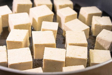 Pieces of tofu are fried in a frying pan.Vegan food ingredient in Asian cuisine, Plant based diet. food concept.