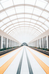 Obraz premium A long, empty train station with a white ceiling and orange stripes on the floor
