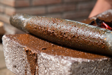 Woman from an indigenous community in Oaxaca preparing traditional Black mole with a metate, a tool for grinding ingredients in Mexico.