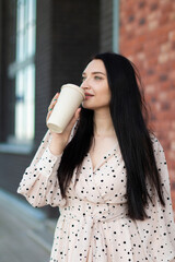 A young woman enjoys a coffee on the street on a summer's day. Lifestyle in the city. A moment of relaxation.