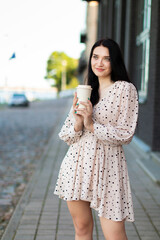 A young woman enjoys a coffee on the street on a summer's day. Lifestyle in the city. A moment of relaxation.