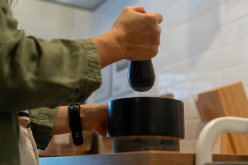 Female hand holds pestle, grinding spices in traditional mortar for cooking