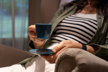 Unidentified woman holding cup of coffee during relax in living room