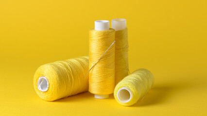 Yellow thread spools with needle background with copy space for text close-up flat lay top view