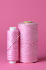 Pink thread spools with needle background with copy space for text close-up flat lay top view