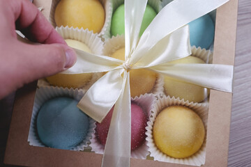 A Hand Carefully Unties A Satin Ribbon On A Box Containing An Assortment Of Colorful, Round Desserts. The Sweets Are Neatly Arranged, Offering A Delightful And Inviting Presentation.