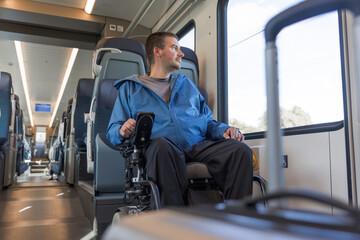 Man with disability on a rail journey, sitting in a wheelchair inside accessible train for people...