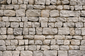 Stone wall is constructed with uneven, rough-cut gray stones. Detail of traditional stone masonry from the South of France.