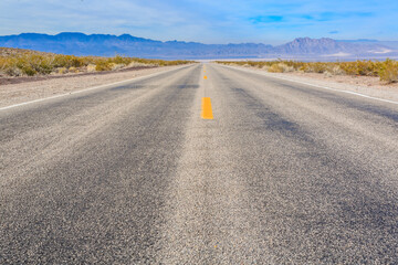 A long, empty road with yellow lines and a blue sky in the background