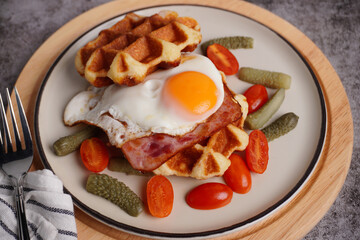 Breakfast waffles with fried eggs Tomatoes and pickled cucumbers In a white plate with a black background