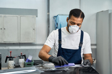 Mechanic in safety gear tackles car repairs in a busy garage.