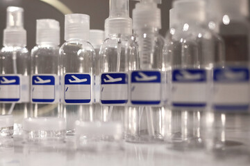 Small, transparent, plastic liquid bottles for plane traveling. Blank label with blue plane icon.